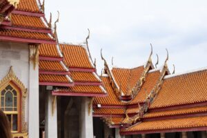 Detailed view of traditional Thai temple roofs with intricate designs under a bright sky.