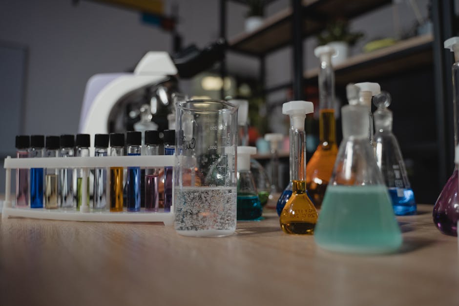 Glassware with colored liquids in a laboratory on a wooden table, showcasing diverse chemical research tools.