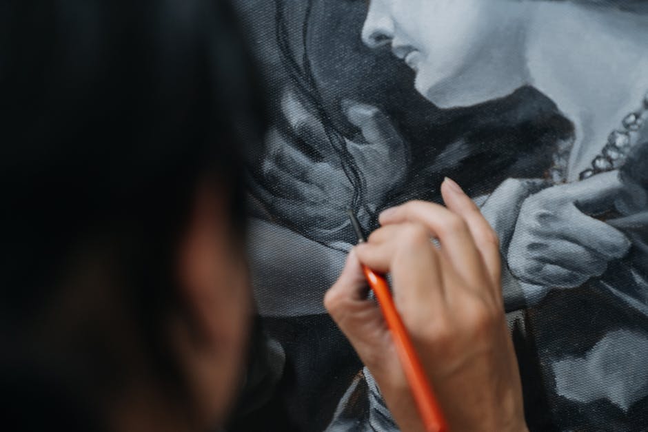 Close-up of artist carefully painting a detailed portrait using fine brushes.