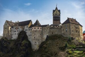 Stunning view of a historic Gothic castle perched on a rocky cliff under a clear sky.