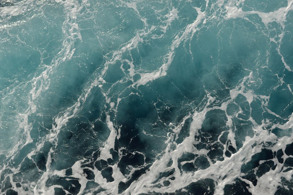 Captivating aerial view of ocean waves with turquoise hues and foamy patterns, perfect for nature and sea themes.